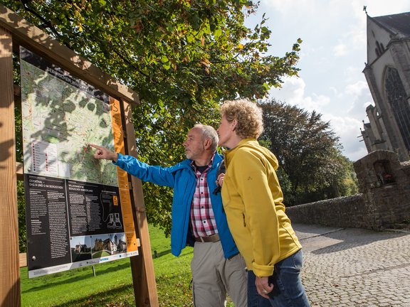 Bergischer Weg führt durch Altenberg Paar an der Infotafel zum Bergischen Weg am Altenberger Dom